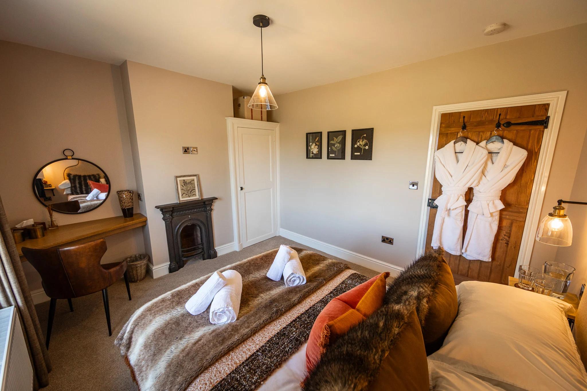 Guest bedroom at Pheasant Cottage, Peplow Hall Estate featuring a double-size bed with soft throws, countryside-inspired décor, a writing desk and luxury robes.