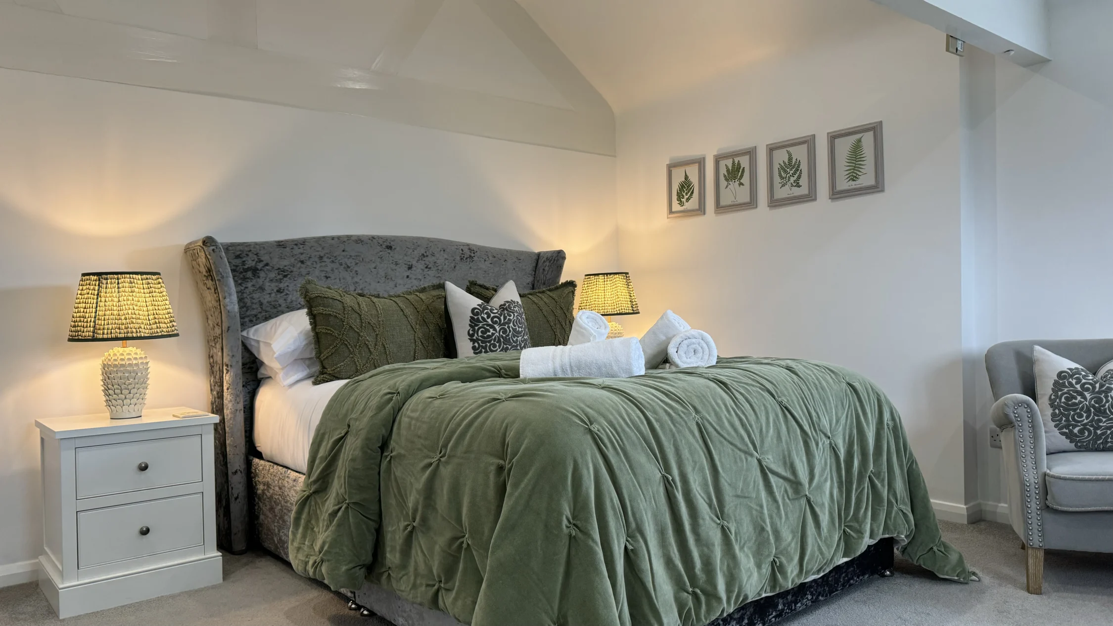 Fox Cottage master bedroom Elegant bedroom in a luxury countryside retreat featuring a plush upholstered bed with green quilted bedding, soft lighting, botanical wall art, and refined modern decor.