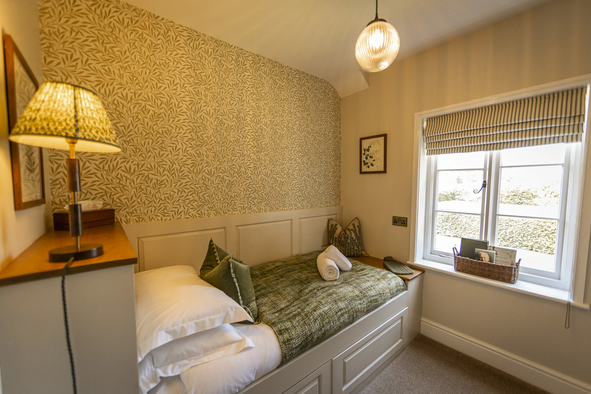 Cosy single bedroom at Owl Cottage, Peplow Hall Estate, Shropshire, featuring a built-in day bed, botanical wallpaper and window overlooking the countryside in a luxury self-catering holiday cottage.