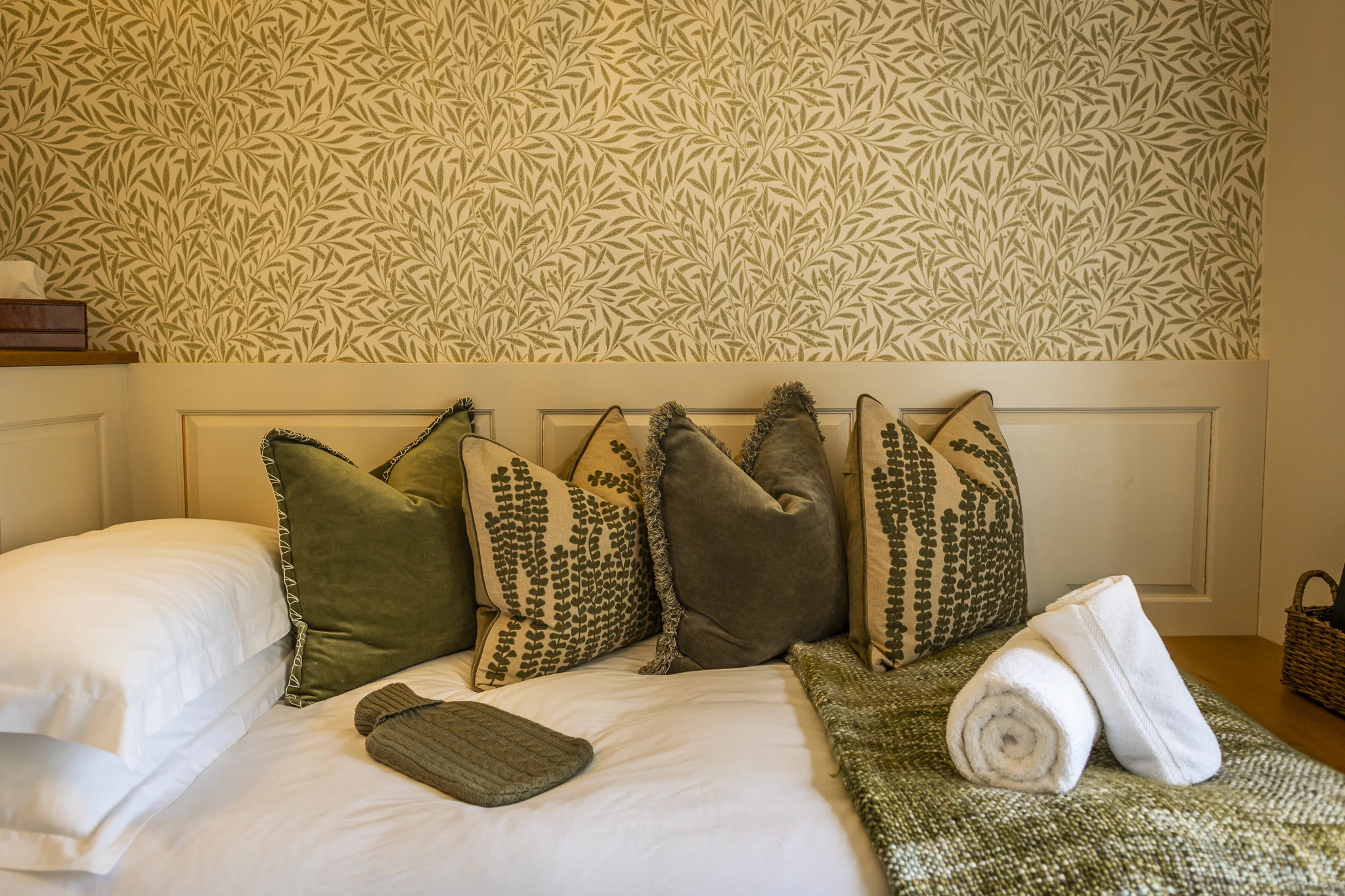 Detail of the single bedroom at Owl Cottage, Peplow Hall Estate, Shropshire, showing a built-in day bed with botanical cushions, soft linens and cosy countryside styling in a luxury self-catering holiday cottage.