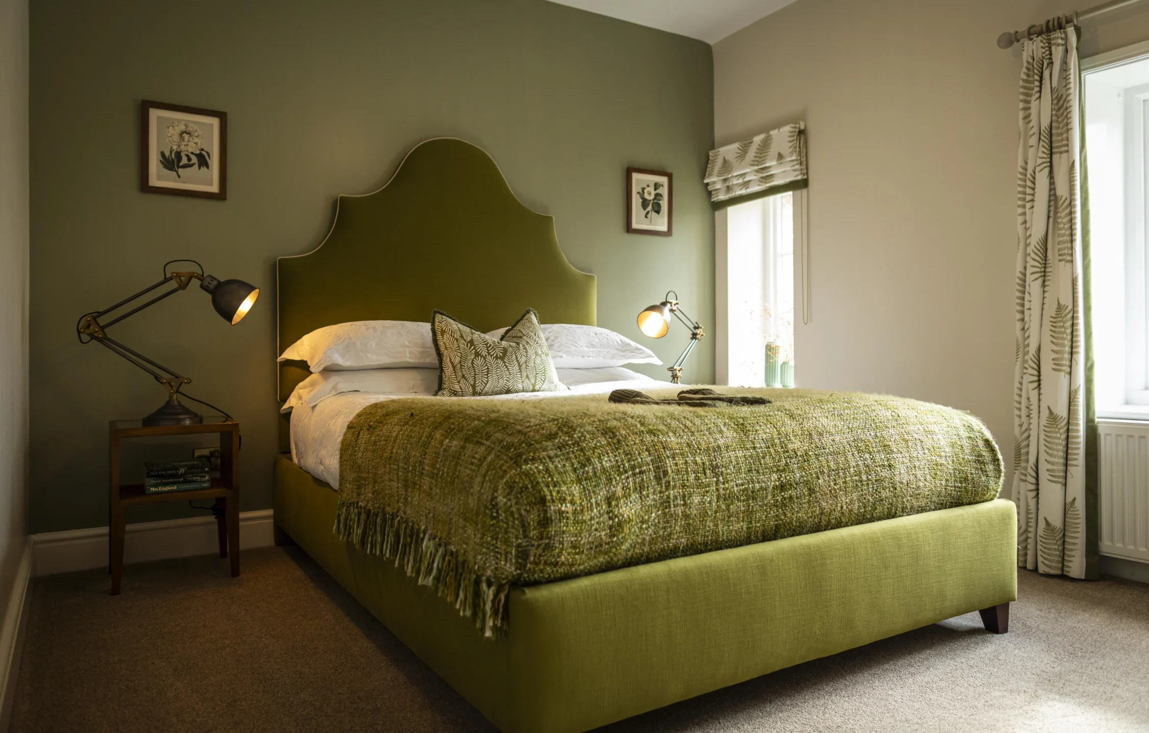 Stylish bedroom at Owl Cottage, Peplow Hall Estate, Shropshire, featuring a green upholstered bed, botanical décor and soft natural light in a luxury self-catering holiday cottage.