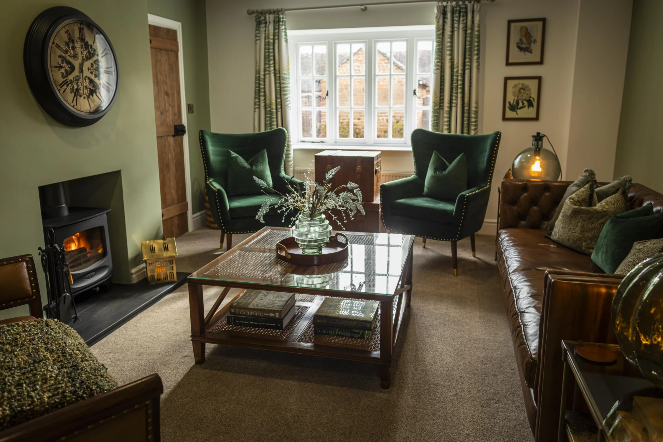 Owl Cottage Living Room Cosy living room at Owl Cottage, Peplow Hall Estate, Shropshire, featuring a wood-burning stove, leather sofa, green armchairs and large window overlooking the countryside in a luxury self-catering holiday cottage.