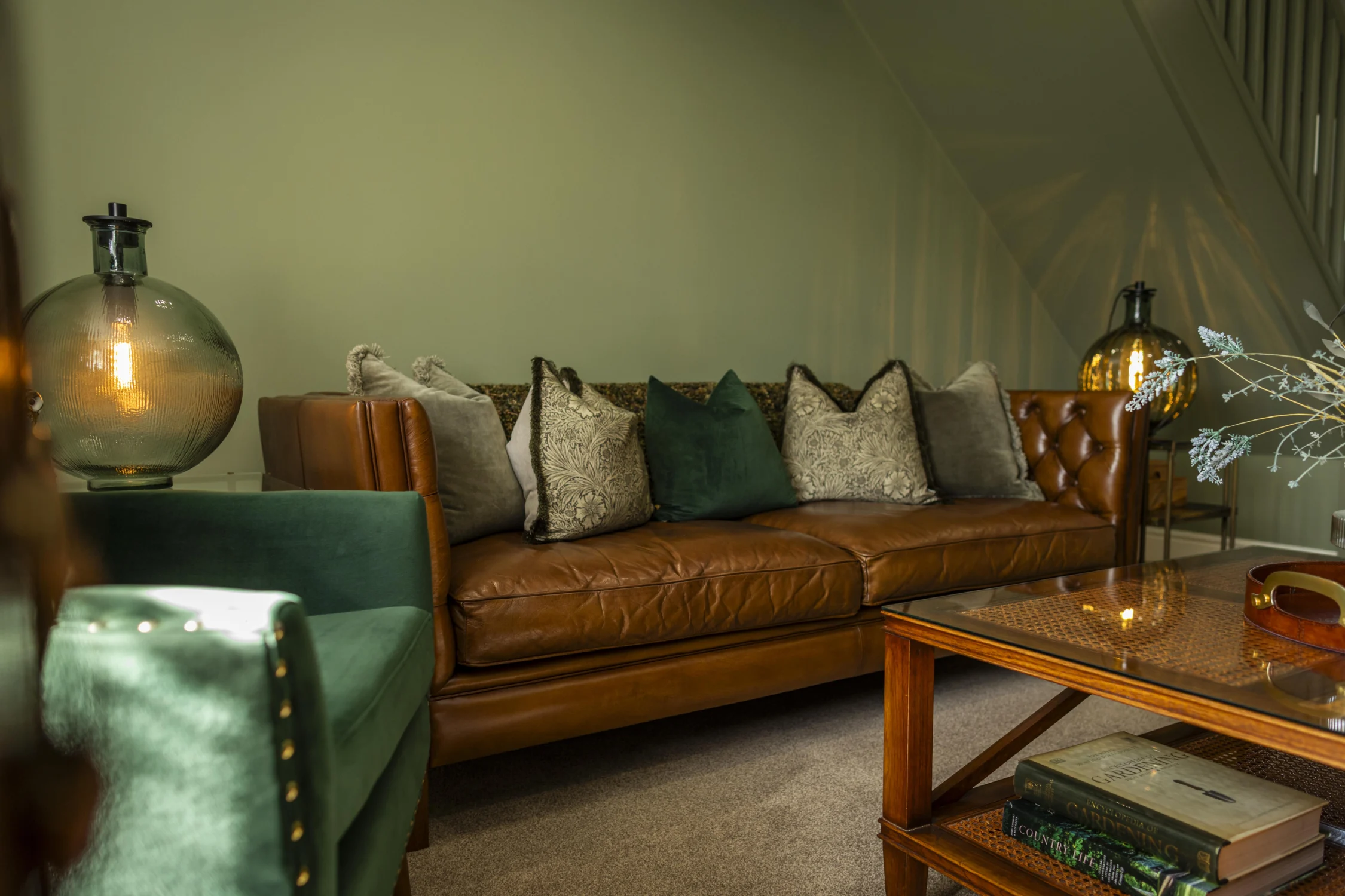 Stylish living area at Owl Cottage, Peplow Hall Estate, Shropshire, featuring a leather sofa, green armchair, glass coffee table and warm ambient lighting in a luxury self-catering holiday cottage.