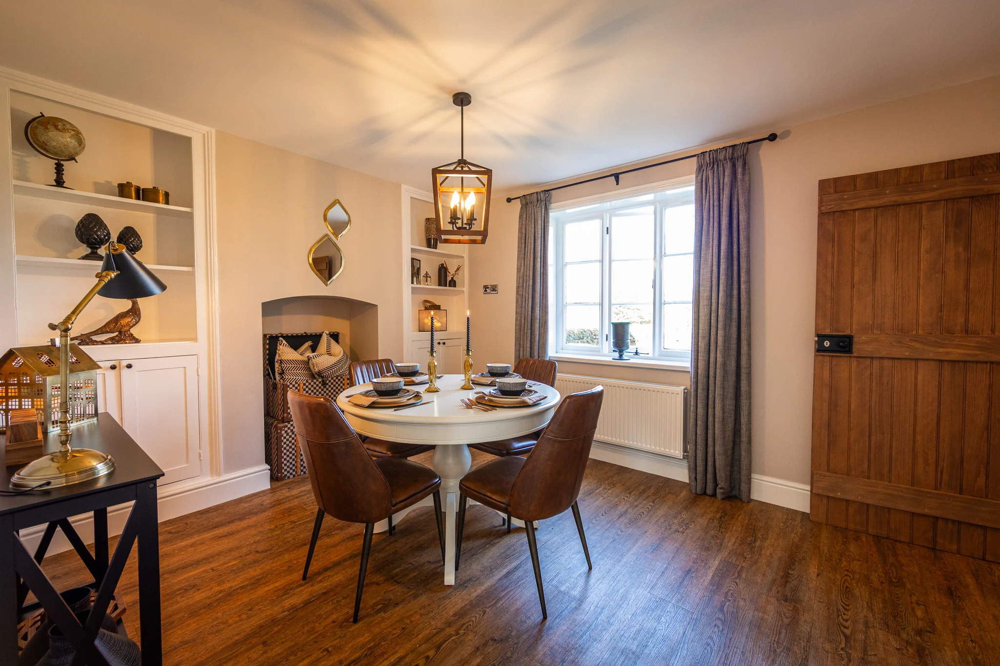 Dining area at Pheasant Cottage, Peplow Hall Estate with round dining table, leather chairs and elegant country house styling.